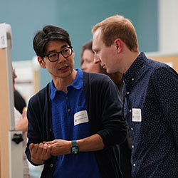 Two male researchers from Seattle Children’s and Washington State University discuss a scientific poster
