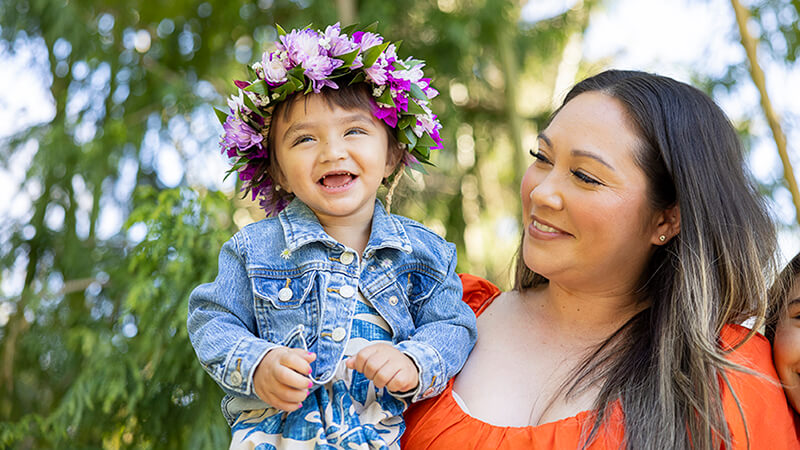 Child wearing crown of flowers with her mother