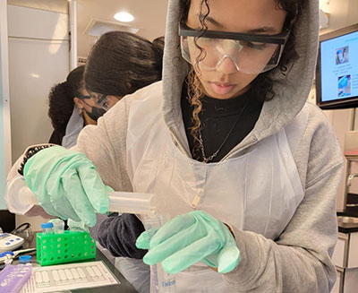 A student pouring a solution into a beaker