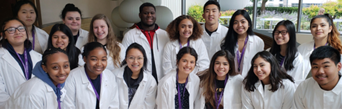 High school students wearing lab coats and smiling for a group photo